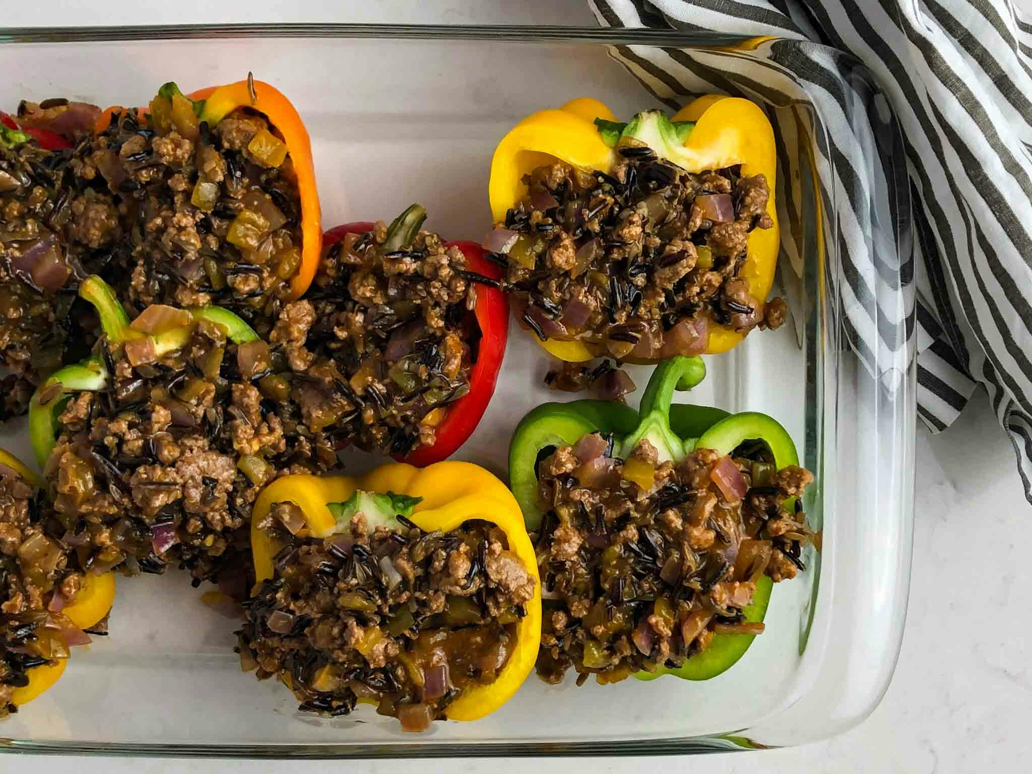 Uncooked beef enchilada stuffed peppers in a glass pan.