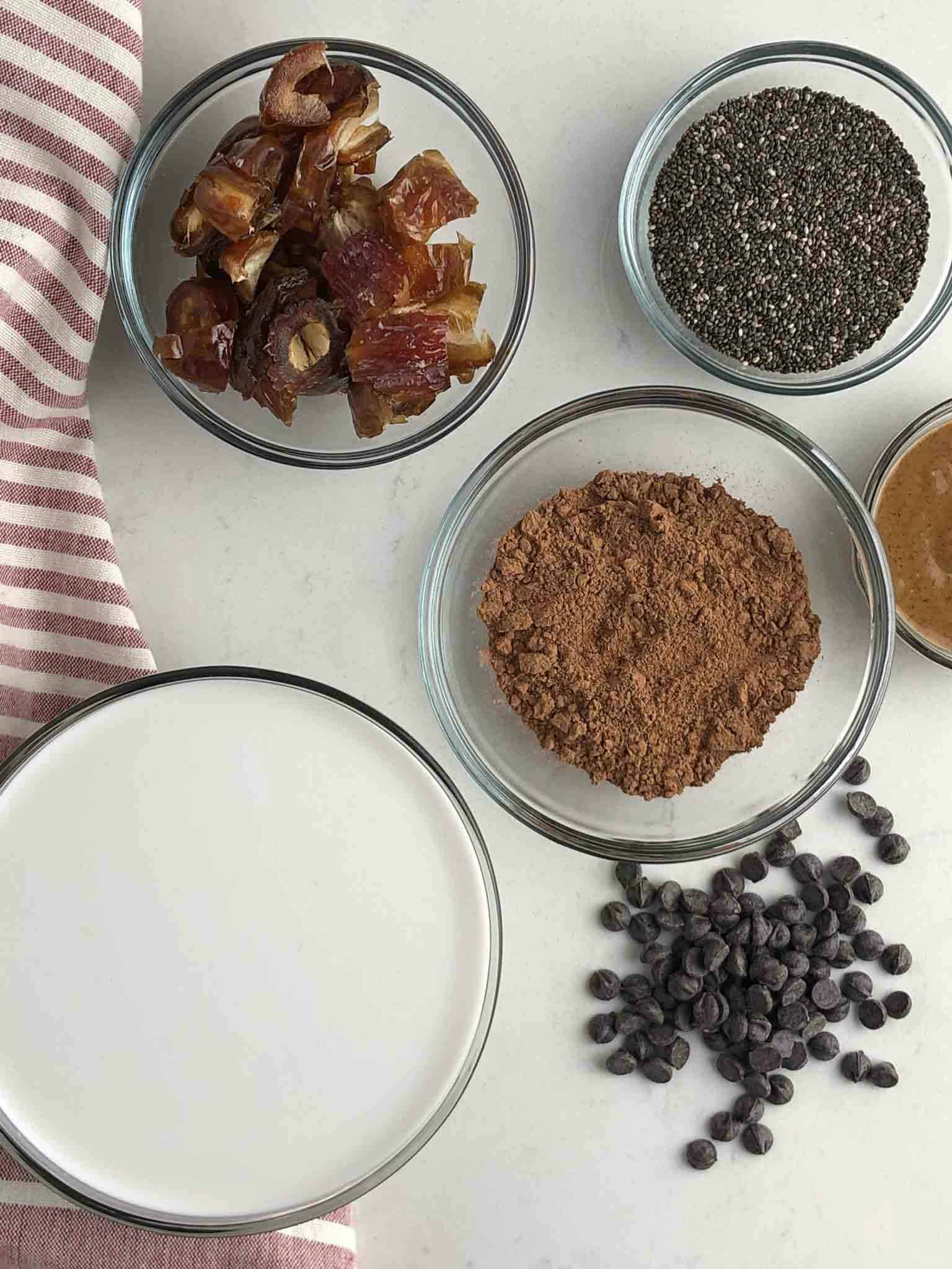 All chocolate chia seed mousse ingredients in bowls laid out on a white table