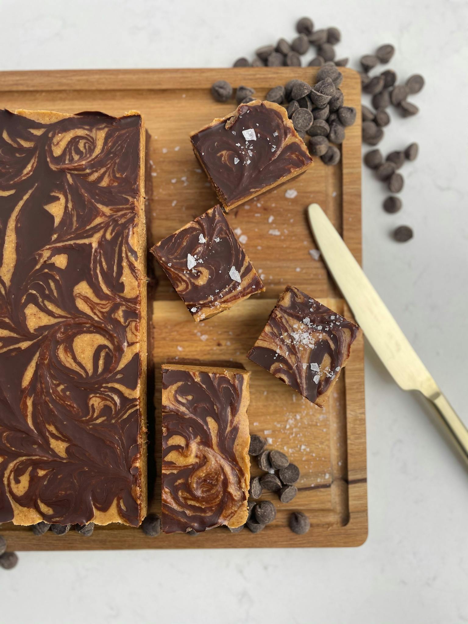 A block of dark chocolate almond butter fudge next to pieces that have been cut.