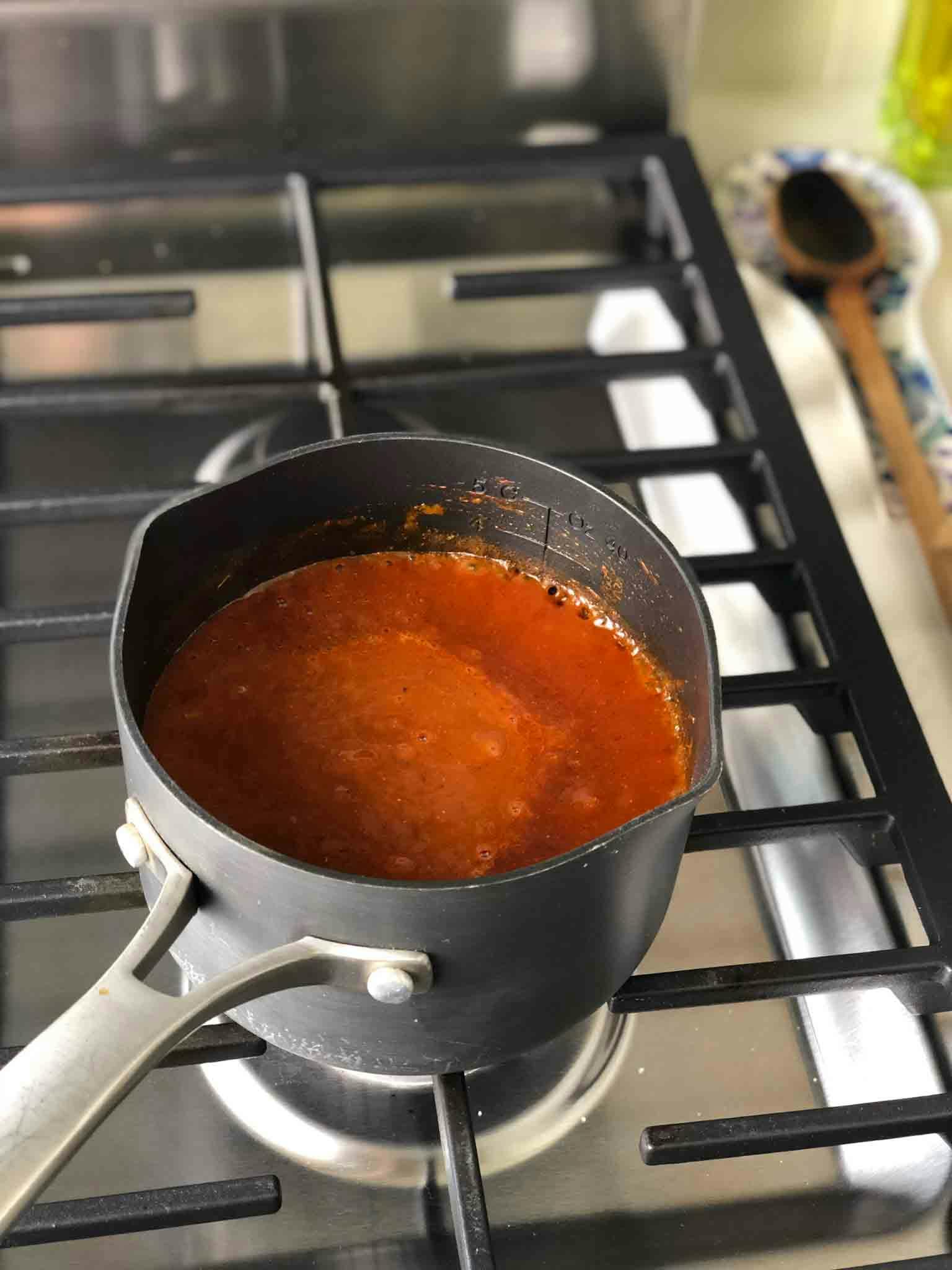 Enchilada sauce cooking in sauce pan on the stove.