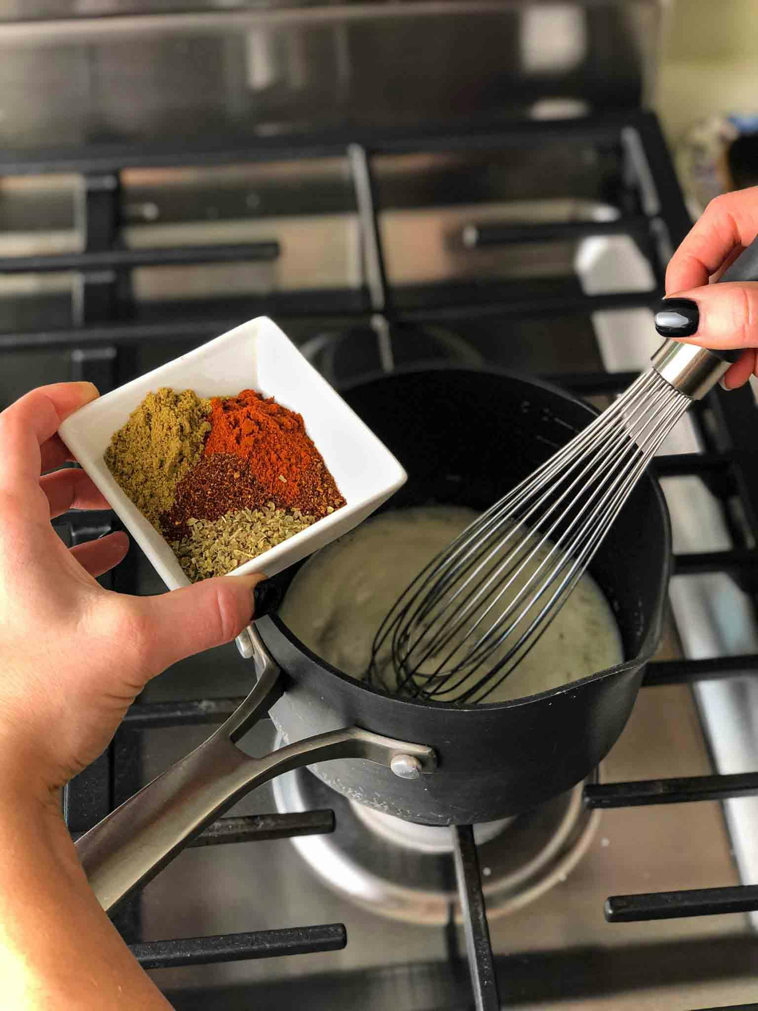 Spices being held over the sauce pan before being included.