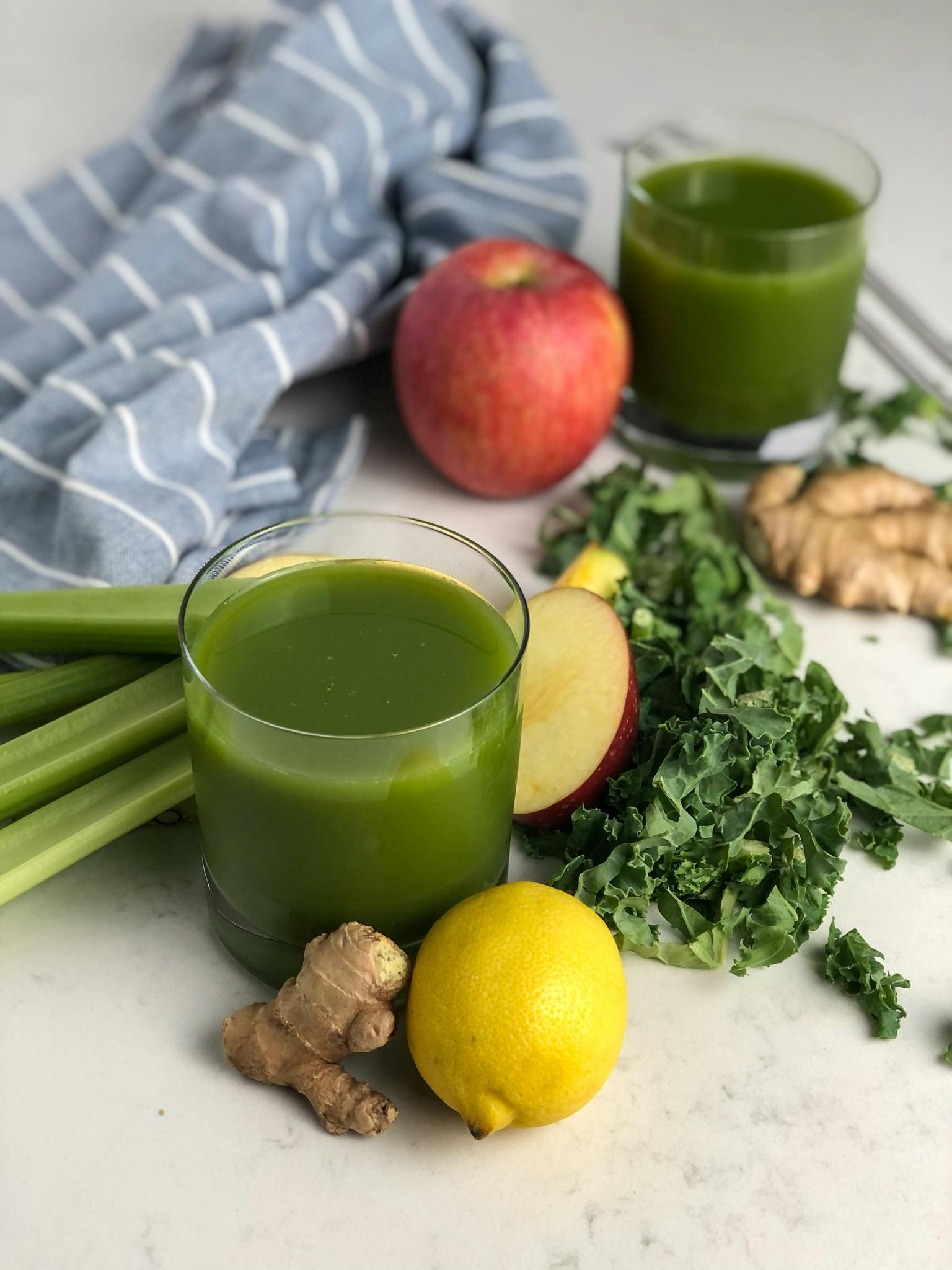 Detox green juice in glasses surrounded by the ingredients.
